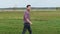 Happy young man walking excitedly in the field at sunset, smiles, feels free, side view.