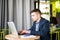 Happy young man works on his laptop to get all his business done early in the morning with his cup of coffee