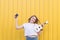 happy young model posing with white ukulele and retro camera on background of yellow wall