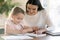 Happy young mom and little daughter study at home