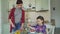 Happy young mother and cheerful daughter cook salad together in the kitchen at home cutting vegetables and talking