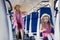 Happy young mother goes with suitcase to her little daughter who sitting on armchair in train