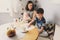 Happy young mother having breakfast in modern kitchen with her baby daughter and kid son