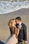 Happy young newly married couple woman in white dress man in love running, have fun on clean sandy beach waves of azure sea or