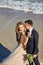 Happy young newly married couple woman in white dress man in love running, have fun on clean sandy beach waves of azure sea or