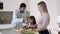 Happy young parents couple and little girl cooking dinner