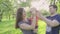 Happy young parents share kiss their cute baby boy outdoors in park. Slow motion