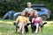 Happy young parents and their kids resting together at camping site in summer