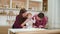 Happy young parents with toddler daughter having fun with flour in kitchen