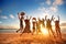 Happy young people jumping at the beach on beautiful sunset