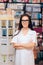 Happy Young Pharmacist Standing Next to Shelves