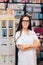 Happy Young Pharmacist Standing Next to Shelves