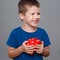 Happy young preschooler holding red dotted piggy bank