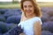 Happy young pretty modest smiling woman enjoying fresh air and aroma at sunset in a lavender field