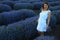 Happy young pretty modest smiling woman enjoying fresh air and aroma at sunset in a lavender field