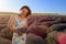 Happy young pretty woman walks at sunset in a lavender field with a bouquet in her hands and enjoys solitude with nature