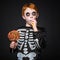 Happy young red hair boy with skeleton costume holding and eating colorful candies