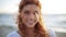 Happy young redhead woman face on beach