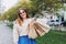 Happy young redhead woman holding shopping paper bags in hands, walking at city street, black friday. Urban lifestyle