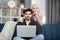 happy young relaxed Muslim couple working on laptop pc at cozy home interior. Handsome man sitting on sofa with laptop