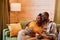 Happy young restful couple with cups of hot tea watching television at home