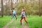 Happy young rock band of two jumping and playing guitar little caucasian girls in green outdoor spring park during rehearsal