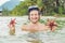 Happy young scuba diver holding sea star, smiling, looking at camera