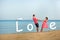 Happy young smiling couple holding hands on the beach. The inscription Love.