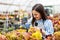 Happy young smiling female working with flowers at greenhouse holding box multicolored plants