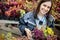 Happy young smiling female working with flowers at greenhouse holding box multicolored plants