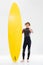 Happy young surfer holding surfboard and showing thumbs up