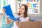 Happy young teenager girl smiling while unpacking parcel with colorful clothes delivered in box by courier