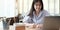 Happy young thai girl with wireless headphones looking at laptop screen, reading listening online courses, studying remotely from