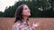 Happy young tourist woman in a plaid shirt looks up with raised arms, enjoying a calm rainy day in nature, breathing