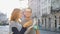 Happy young tourists couple holding a paper map of ancient European city early in the morning on empty square and