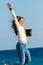 Happy young tween girl jumping with headphones and tablet on beach