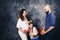 Happy young vegan family. pregnant mother, bearded father, and little daughter are holding apples in their hands and smile