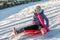 Happy young vibrantly dressed girl sledging with blue ear muffs