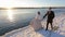 Happy young wedding couple walking next to bank of river outdoors