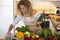 Happy young woman in apron cooking in kitchen. Smiling woman holding fresh vegetable in kitchen. Healthy and proper nutrition on a