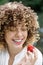 Happy young woman with beautiful curly hair chooses healthy food and eat berries. Portrait of a woman eating