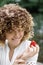 Happy young woman with beautiful curly hair chooses healthy food and eat berries. Portrait of a woman eating