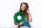 Happy young woman in big black professional dj headphones holding trendy green colorful vinyl record posing against white studio b