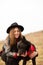 Happy young woman with black hat, plaing with her black dog on the shore of the lake