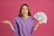 Happy young woman with cash money on pink background