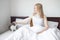 Happy young woman with cat in bed at home. Pets, morning, comfort, rest and people concept.