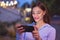 Happy young woman checking social media at evening outdoors