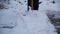 Happy young woman cleans snow in the garden near the house. Portrait of a girl with a snow shovel in her hands. Happy girl removes