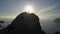 Happy young woman climbs to the top of high mountain. Lady reaching the summit in beautiful scenery over a sea at sunset