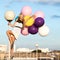 Happy young woman with colorful latex balloons